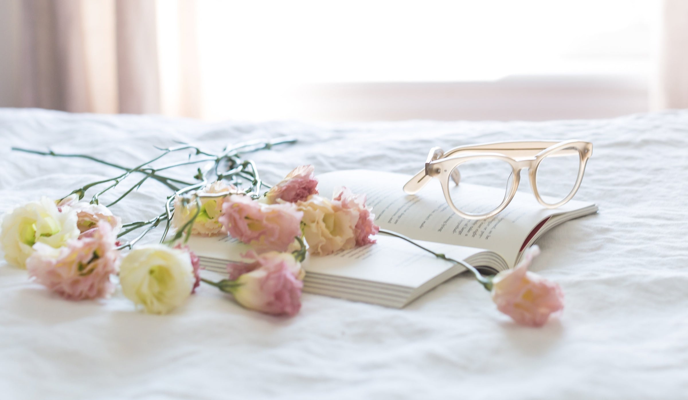Journal with glasses and flowers lating on a bed in a well lit room.  Chosen as secondary banner for Journal, tips, articles & good news for Eden Tree Eco website.
