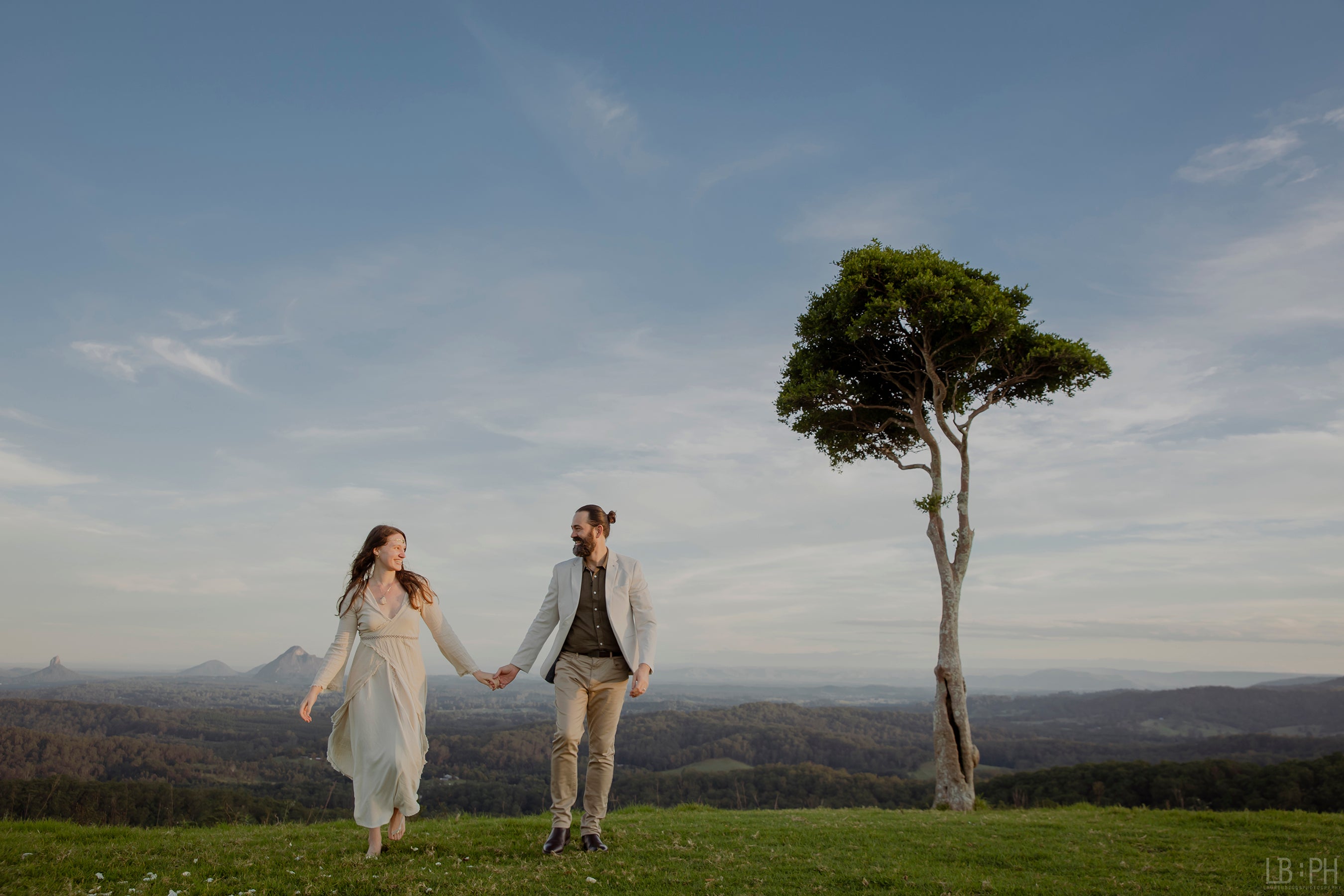 Eden Tree Eco - Co-Creators walking hand in hand against the backdrop of a beautiful tree overlooking a fantastical landscape.